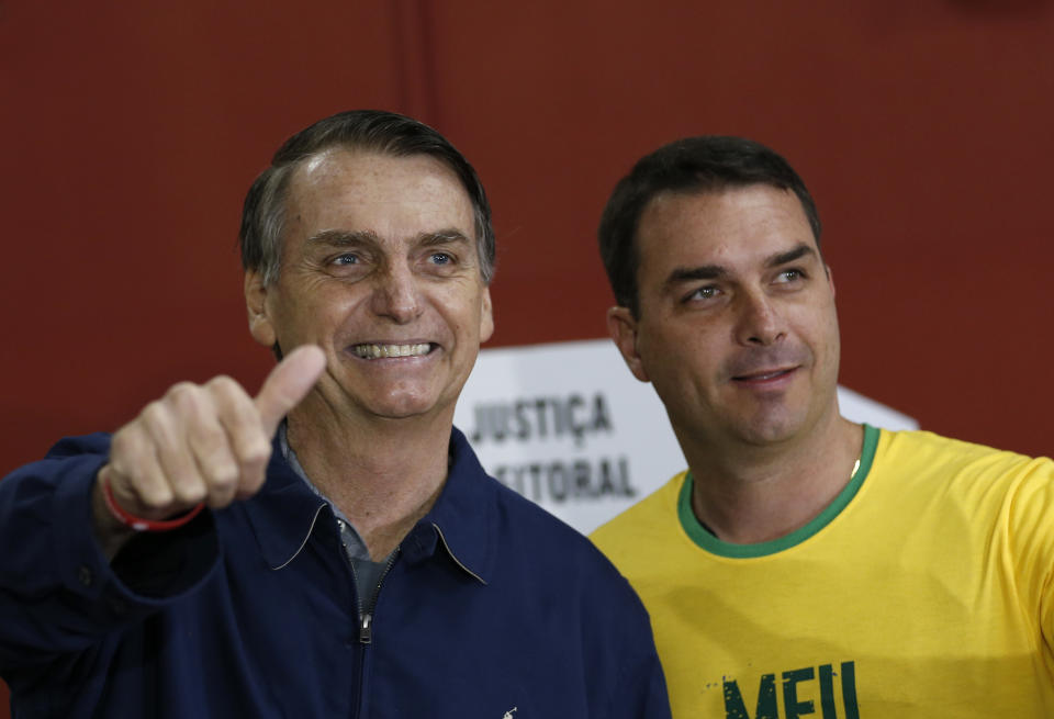 Presidential frontrunner Jair Bolsonaro, of the Social Liberal Party, left, accompanied by his son Flavio Bolsonaro, flashes a thumbs up as he arrives to vote in the general election, in Rio de Janeiro, Brazil, Sunday, Oct. 7, 2018. Brazilians choose among 13 candidates for president Sunday in one of the most unpredictable and divisive elections in decades. If no one gets a majority in the first round, the top two candidates will compete in a runoff. (AP Photo/Silvia Izquierdo)