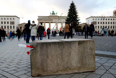 FILE PHOTO: People walk beside a concrete barrier at the Brandenburg Gate, ahead of the upcoming New Year's Eve celebrations in Berlin, Germany December 27, 2016. REUTERS/Fabrizio Bensch/File Photo