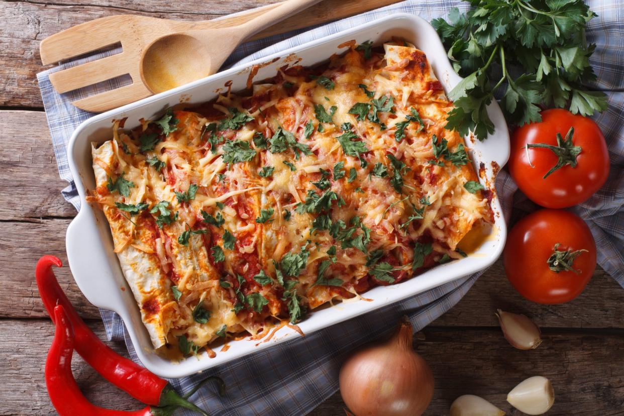 Mexican enchilada in a baking dish with the ingredients on the table close-up. horizontal view from above