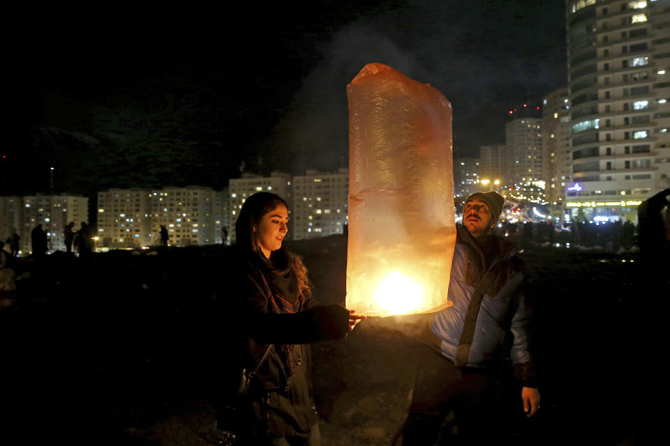 Two Iranians release a lit lantern during a celebration, known as "Chaharshanbe Souri," or Wednesday Feast, marking the eve of the last Wednesday of the solar Persian year, Tuesday, March 19, 2019 in Tehran, Iran. Iran's many woes briefly went up in smoke on Tuesday as Iranians observed a nearly 4,000-year-old Persian tradition known as the Festival of Fire. (AP Photo/Ebrahim Noroozi)
