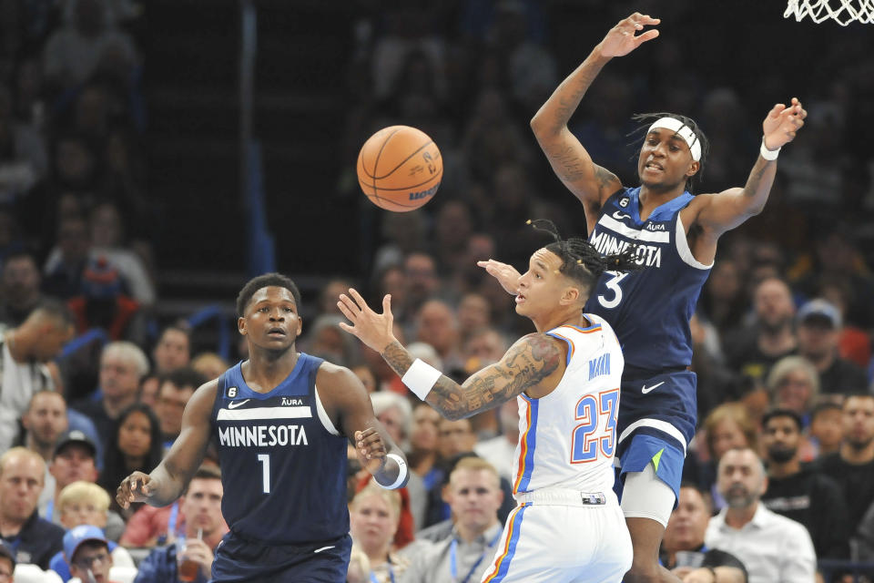 Oklahoma City Thunder guard Tre Mann (23) tries to keep the ball away from Minnesota Timberwolves forwards Anthony Edwards (1) and Jaden McDaniels (3) in the second half of an NBA basketball game, Sunday, Oct. 23, 2022, in Oklahoma City. (AP Photo/Kyle Phillips)
