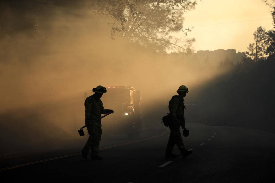 FILE - Two firefighters watch for spot fires, Oct. 13, 2017, near Calistoga, Calif. (AP Photo/Jae C. Hong, file)