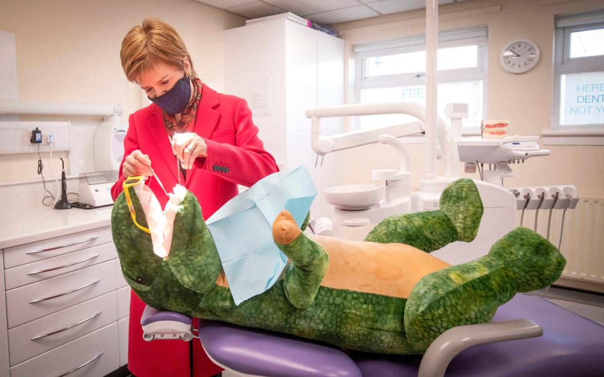 Nicola Sturgeon checks the teeth of 'Dentosaurus' during a visit to the Thornliebank Dental Care centre in Glasgow during the election campaign - Jane Barlow/PA