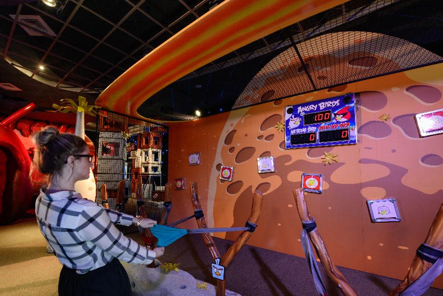 This March 22, 2013 photo shows guests taking their best shot in a competition with fellow players using mini-Angry Birds launched in a slingshot to zap space pigs at the Kennedy Space Center Visitor Complex in Cape Canaveral, Fla. The online game Angry Birds is the inspiration for the new attraction at the space center, where most of the exhibits focus on space exploration and NASA history. (AP Photo/Delaware North, Joe Cascio)