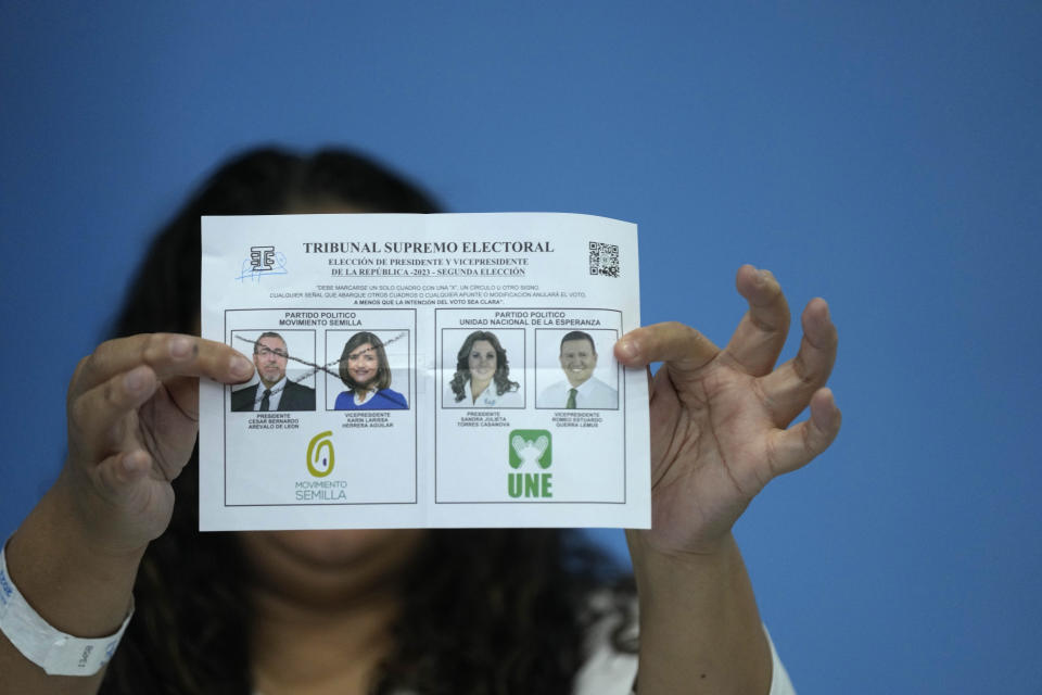 An electoral worker holds up a marked ballot during the vote count for the runoff presidential election, after polls closed, in Guatemala City, Sunday, Aug. 20, 2023. Bernardo Arévalo, of the Seed Movement party, and former first lady Sandra Torres, of the National Unity of Hope party or UNE, are competing to be the country's next president.(AP Photo/Moises Castillo)
