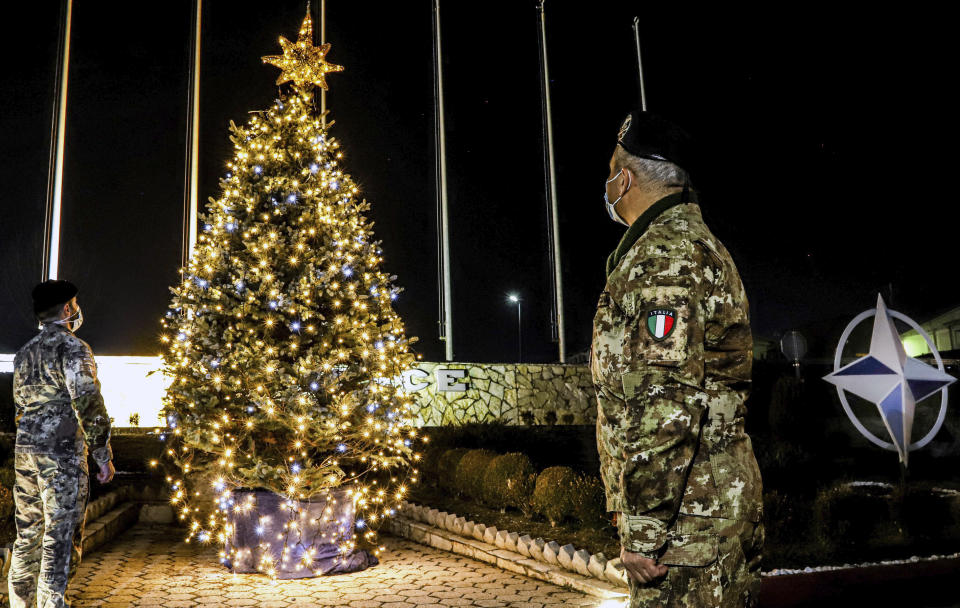 In this photo provided by NATO-led peacekeeping mission in Kosovo (KFOR), Italian soldiers watch Christmas tree on the Christmas Eve in the KFOR military headquarters in Kosovo capital Pristina, Thursday, Dec. 24, 2020. The coronavirus pandemic has totally changed Christmas time operation method and celebrations for the Kosovo Force but it has left unchanged its mission: keeping Kosovo safe and secure for 22 years now on. (KFOR via AP)