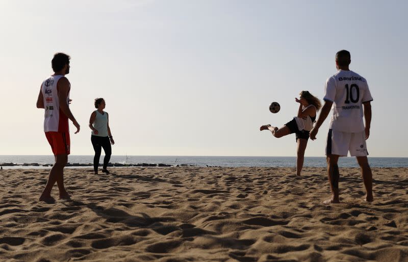 Gente juega mientras disfruta del tiempo soleado en la playa de la Barceloneta, en Barcelona