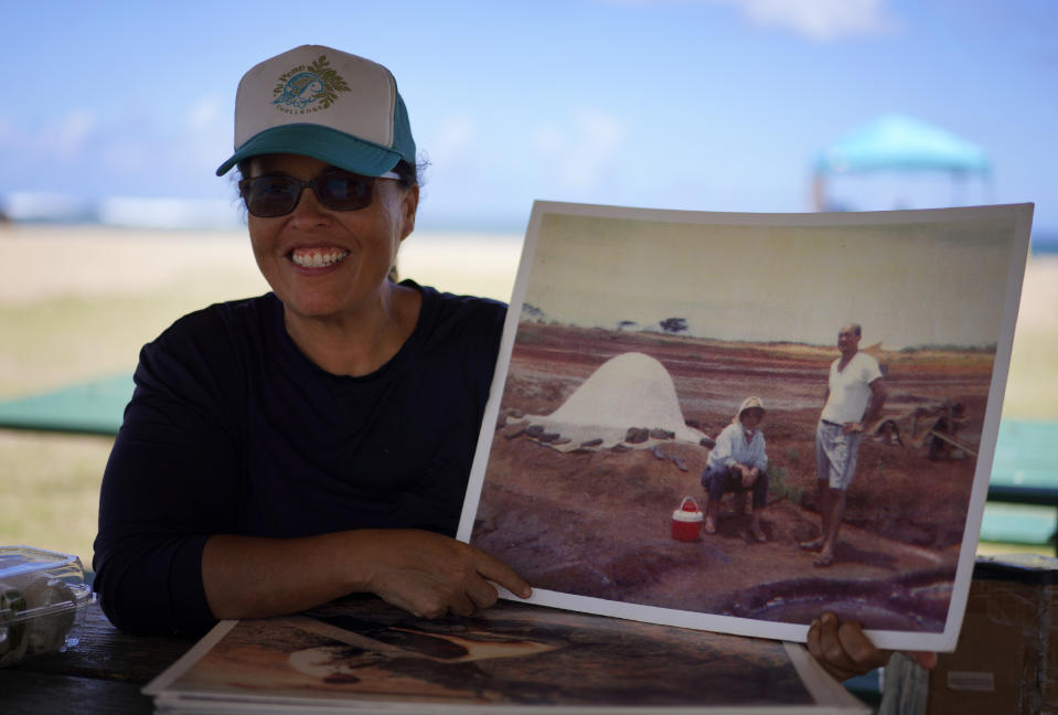 Malia Nobrega-Olivera shows a photo of her grandparents making Hawaiian salt, or "paakai," while sitting at Salt Pond Beach Park in Hanapepe, Hawaii on Sunday, July 10, 2023. (AP Photo/Jessie Wardarski)