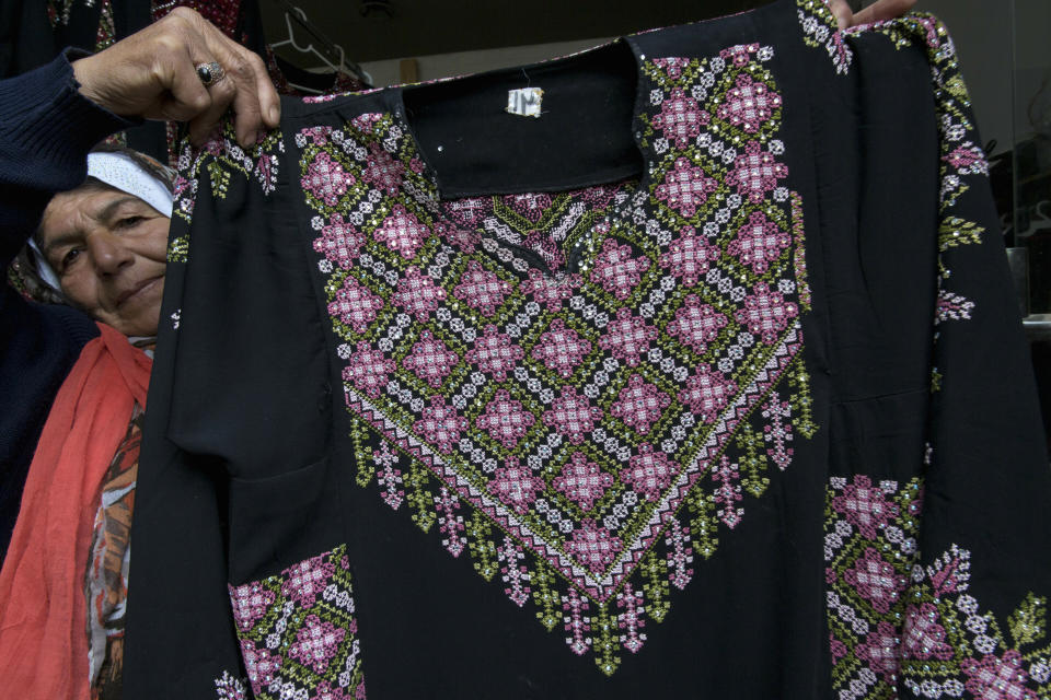 In this Monday, Jan. 28, 2019 photo, Samiha Jeheshat, displays a handmade embroidered Palestinian thobe at her showroom in the West Bank village of Idna, north of Hebron. The thobe is gaining prominence as a softer symbol of Palestinian nationalism, competing with the classic keffiyeh. Rashida Tlaib proudly wore her thobe to her historic swearing-in as the first Palestinian American member of Congress, inspiring women around the world to tweet photos of themselves in their ancestral robes. (AP Photo/Nasser Nasser)