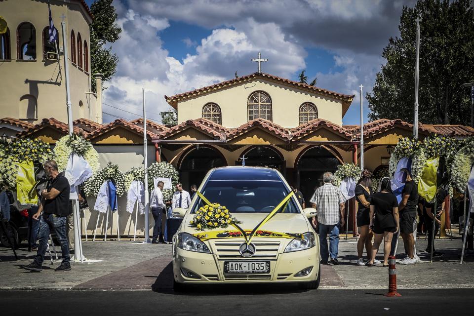 People stand outside a church during the funeral of AEK Athens fan Michalis Katsouris, in Athens, Greece, Friday, Aug. 11, 2023. A funeral service has been held near Athens for the Greek soccer fan killed in an attack led by Croatian supporters that has rattled European sporting officials. (Thanassis Dimopoulos/Eurokinissi via AP)