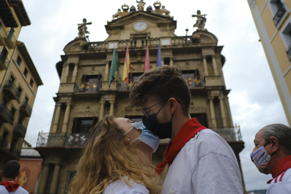 Aitana Agudo and Iraitz Iriarte, right, wearing face protection, kiss in front of the City Hall in Pamplona, northern Spain, Tuesday July 6, 2021, on the day the ''txupinazo'' would usually take place to start the famous San Fermin festival, which was canceled for another year due to the COVID-19 pandemic. (AP Photo/Alvaro Barrientos)