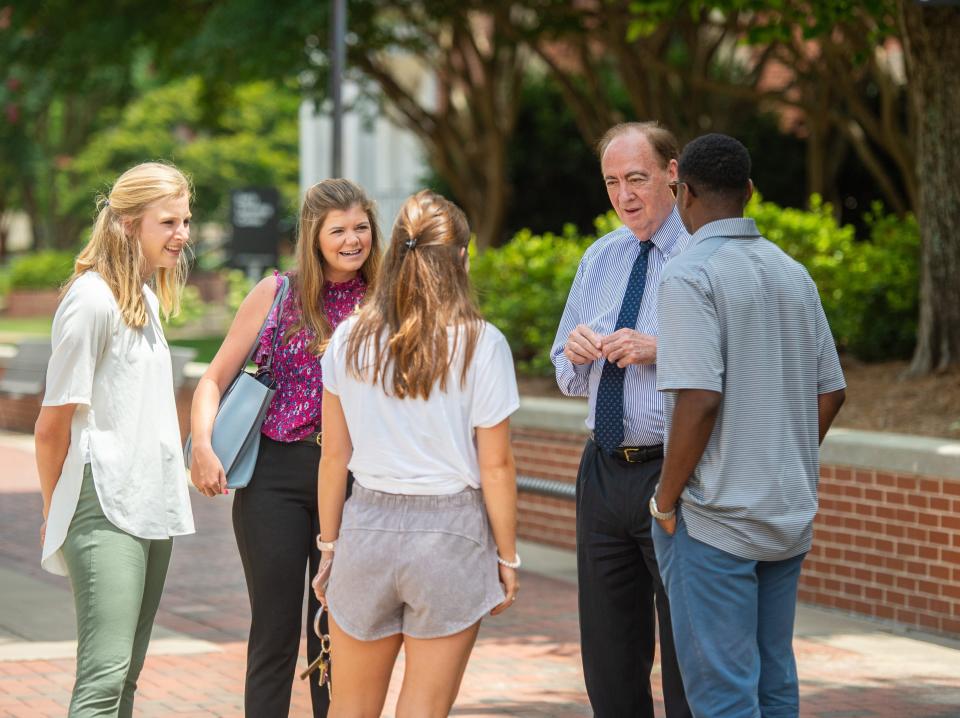 Auburn University President Jay Gogue interacting with four students on Auburn’s campus