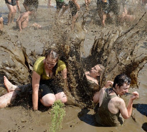 Festival goers jump into muddy water during the opening of the Woodstock Station music festival in Kostrzyn nad Odra