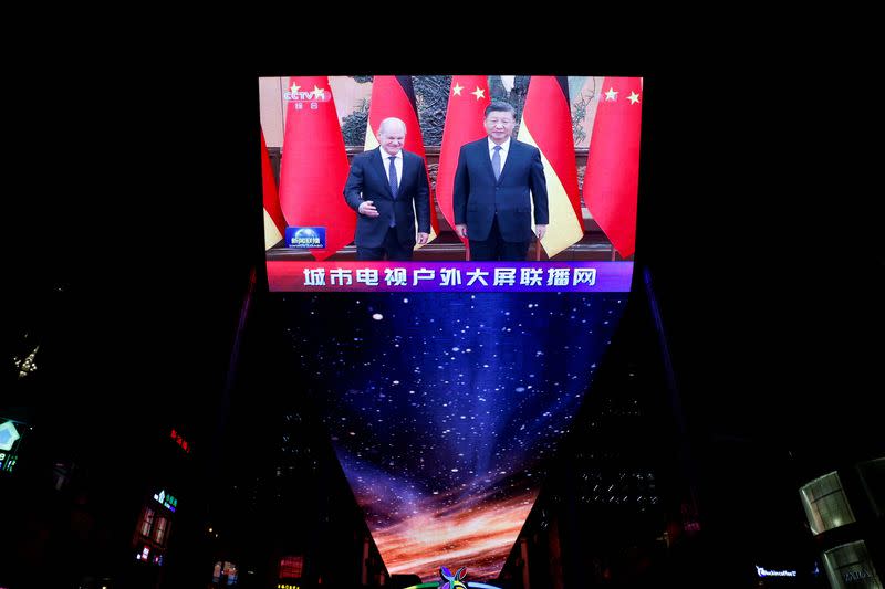 A screen broadcasts a news segment about German Chancellor Olaf Scholz meeting Chinese President Xi Jinping, in Beijing