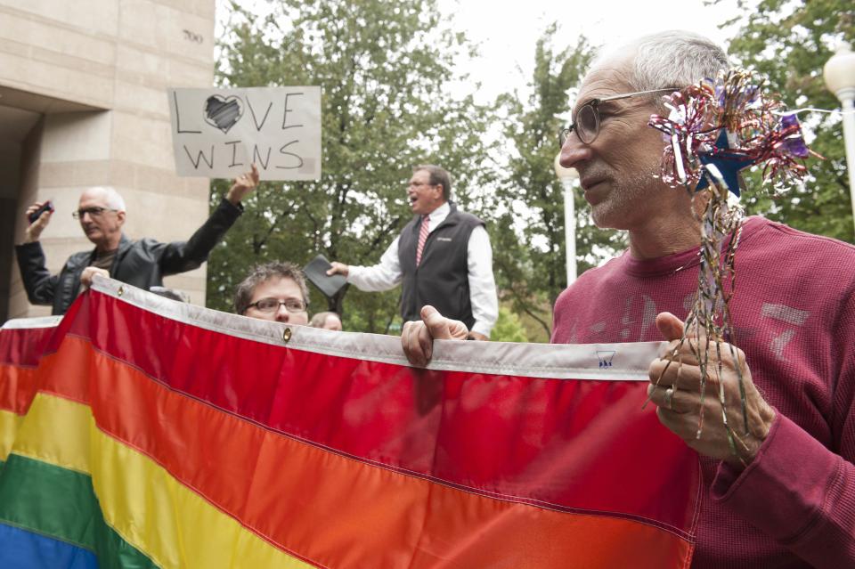 Larry Ferri (R) and Brandi Morris (C) hold large rainbow flag as gay couples marry outside of Mecklenburg County Register of Deeds office in Charlotte, North Carolina, October 13, 2014. Monday was the first day that Mecklenburg County issued marriage licenses to gay couples. Two protesters were at the gathering, but pro-gay rights activists blocked the protesters from interfering with ceremonies. REUTERS/Davis Turner (UNITED STATES - Tags: POLITICS SOCIETY)