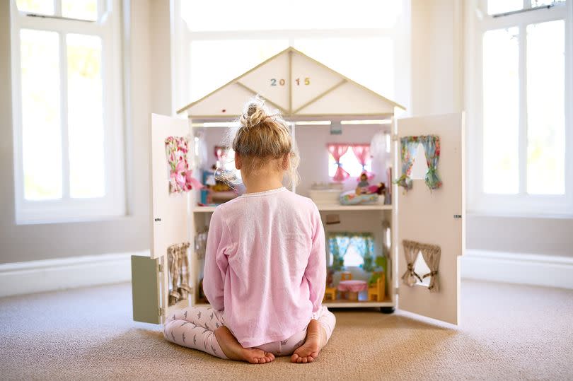 Shot of a little girl playing with her dollhouse at home