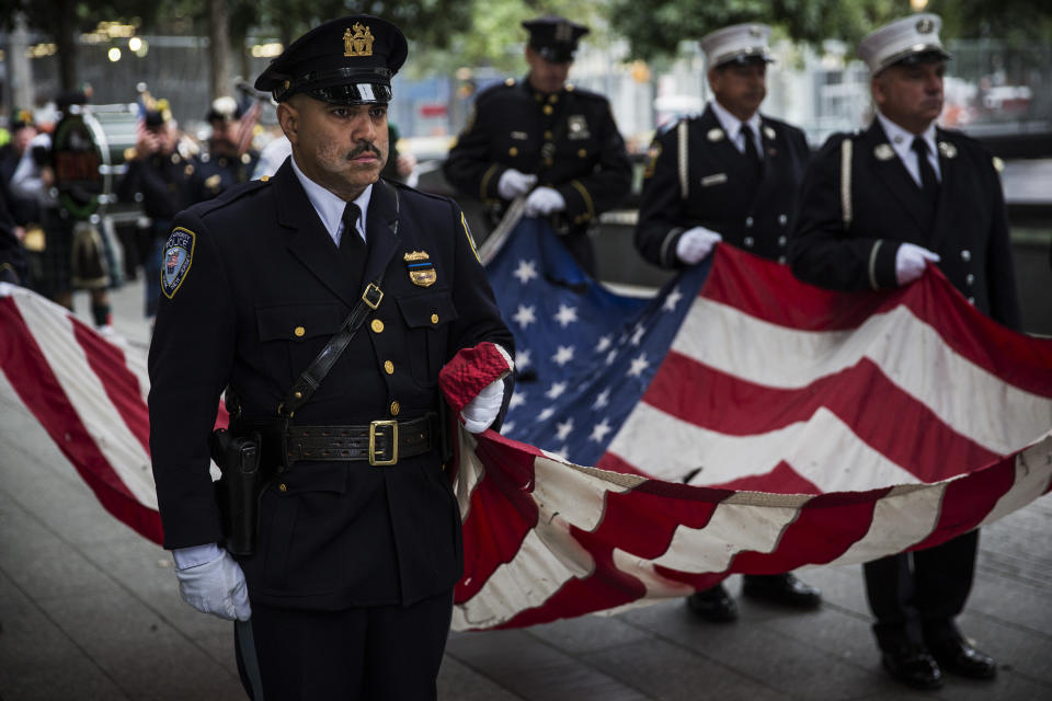 NEW YORK, NY - SEPTEMBER 11: Members of the New York Police Department, Fire Department of New York and Port Authority Police Department carry an American flag past one of the reflecting pools at the beginning of the memorial observances held at the site of the World Trade Center on September 11, 2014 in New York City. This year marks the 13th anniversary of the September 11th terrorist attacks that killed nearly 3,000 people at the World Trade Center, Pentagon and on Flight 93. (Photo by Andrew Burton/Getty Images)