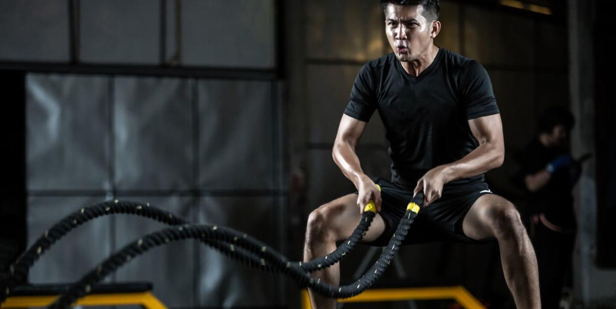 asian man with battle rope battle ropes exercise in the fitness gym, exercises concept