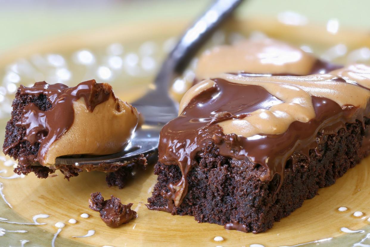 Closeup of peanut butter swirl chocolate brownies with a fork cutting through one piece on a plate with a blurred background
