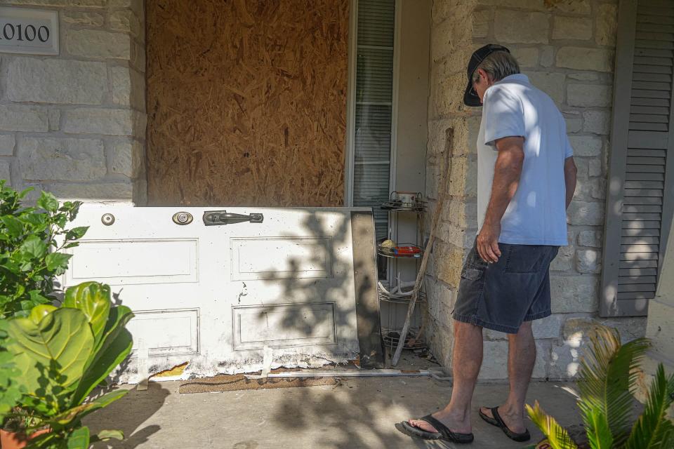 Glen Shield looks at the ruined front door that a SWAT team blew off his house.