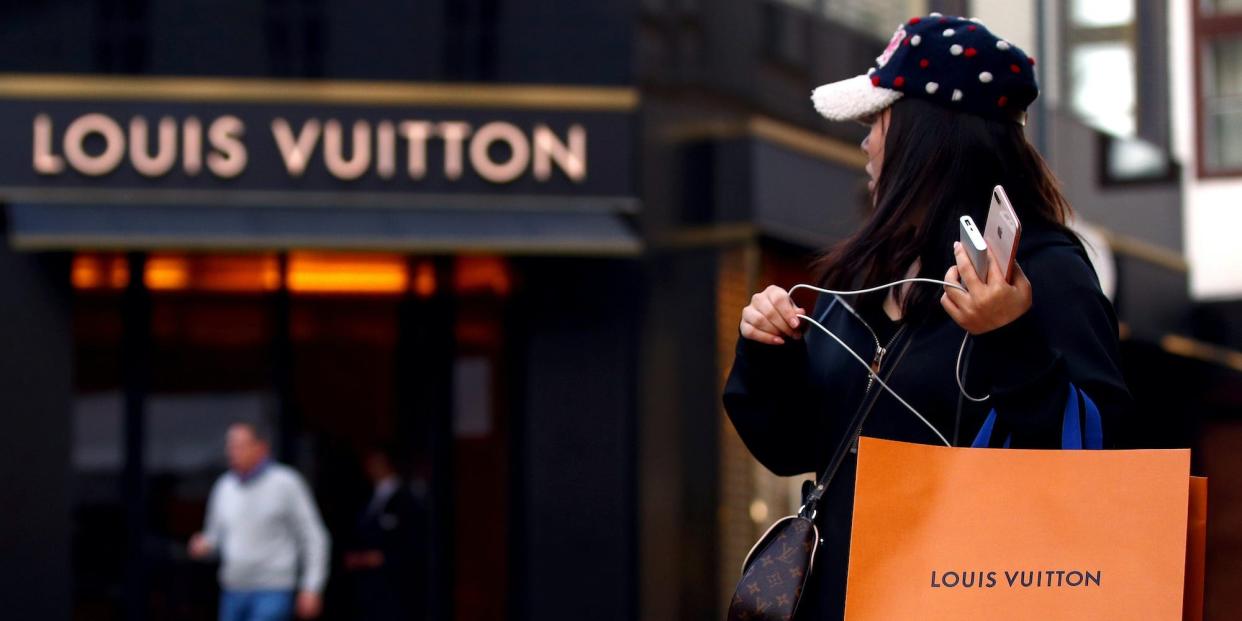 A woman with a Louis Vuitton-branded shopping bag looks towards the entrance of a branch store by LVMH in Vienna, Austria