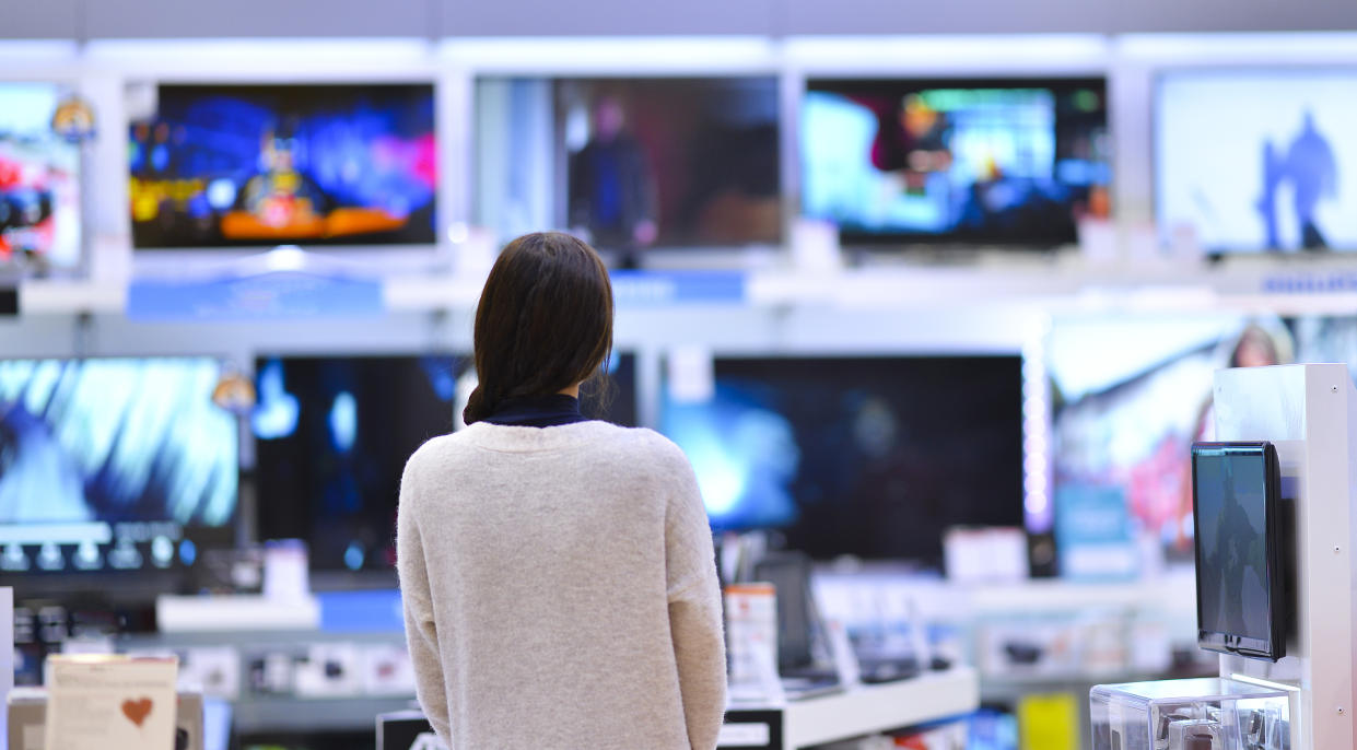 A woman looking at a wall of televisions