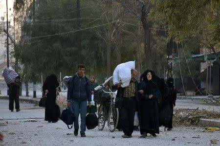 People, who evacuated the eastern districts of Aleppo, carry their belongings as they arrive in a government held area of Aleppo, Syria, in this handout picture provided by SANA on December 7, 2016. SANA/Handout via REUTERS