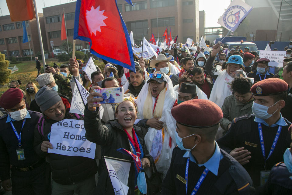 A Nepalese woman takes selfie with the all-Nepalese mountaineering team that became the first to scale Mount K2 in winter as they arrive at Tribhuwan International airport in Kathmandu, Nepal, Tuesday, Jan. 26, 2021. (AP Photo/Niranjan Shrestha)