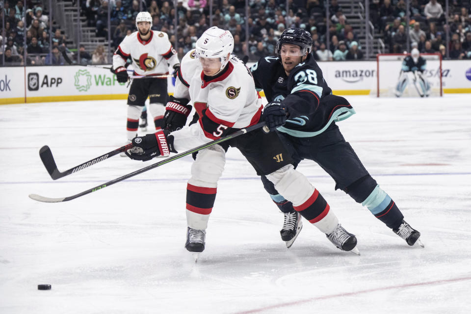 Seattle Kraken forward Jesper Froden, right, and Ottawa Senators defenseman Nick Holden vie for the puck during the second period of an NHL hockey game Thursday, March 9, 2023, in Seattle. (AP Photo/Stephen Brashear)