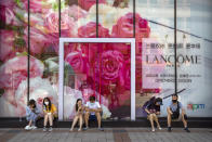 People wearing face masks to protect against the new coronavirus sit in front of a Lancome cosmetics store under construction at a pedestrian shopping street in Beijing, Saturday, June 6, 2020. China's capital is lowering its emergency response level to the second-lowest starting Saturday for the coronavirus pandemic. That will lift most restrictions on people traveling to Beijing from Wuhan and surrounding Hubei province, where the virus first appeared late last year. (AP Photo/Mark Schiefelbein)