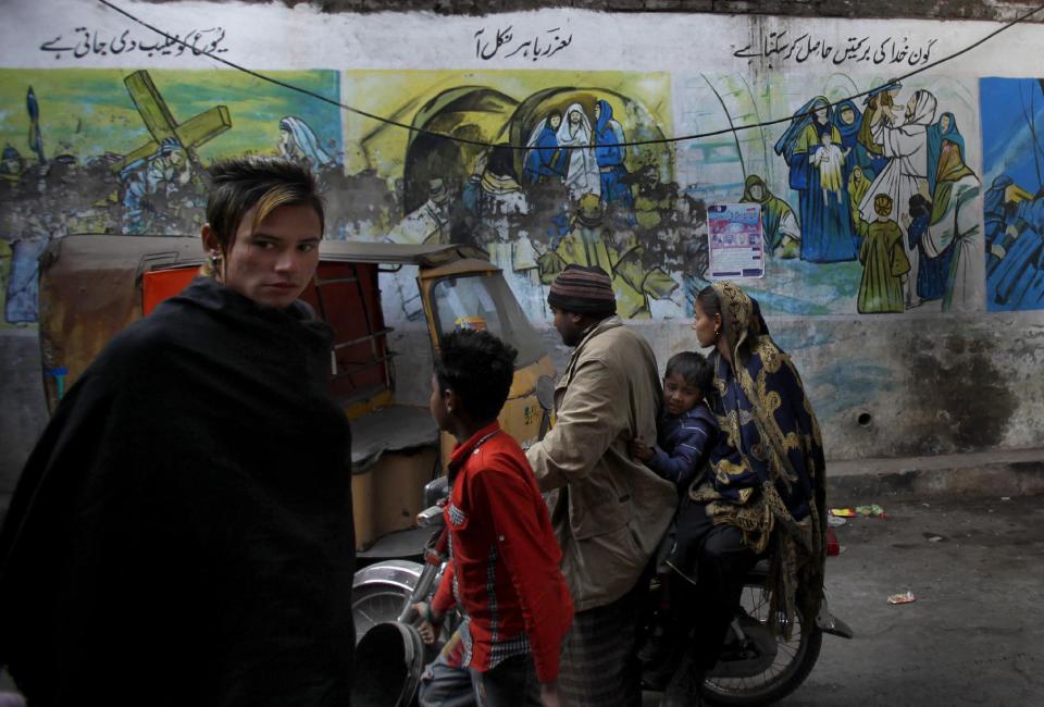 In this Saturday, Jan. 11, 2014 photo, Pakistani Christians walk in a Christian neighborhood, which was torched last March by radical Muslim mobs in Lahore. Pakistan’s blasphemy law has become a potent weapon in the arsenal of Muslim extremists, who use it against adherents of minority religions. (AP Photo/Anjum Naveed)