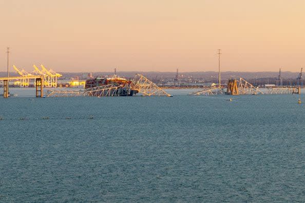 The steel frame of the Francis Scott Key Bridge sits on top of a container ship after it struck the bridge in Baltimore, Maryland, on March 26, 2024. The collapsed sent multiple vehicles and up to 20 people plunging into the harbor below. 