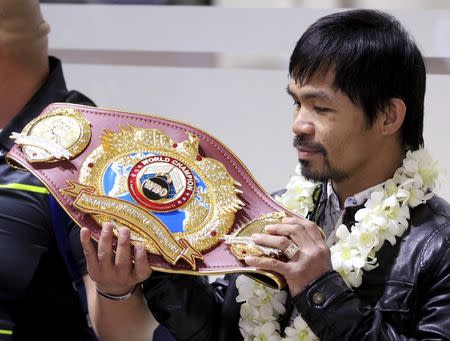 Filipino boxing champion Manny Pacquiao looks at his WBO championship belt after defeating Timothy Bradley, upon his arrival at the Ninoy Aquino International Airport in Manila April 14, 2016. REUTERS/Romeo Ranoco