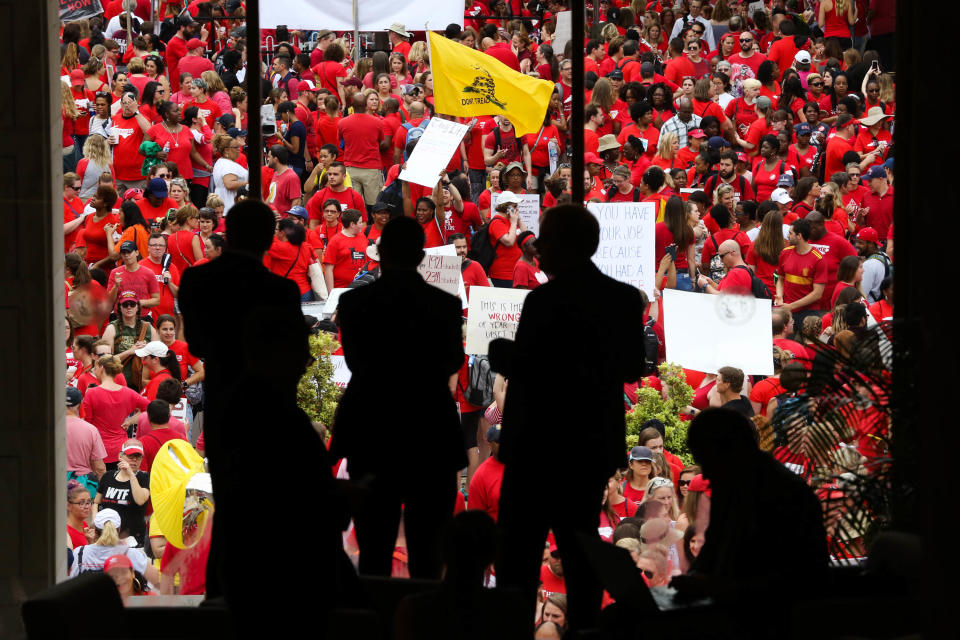 Three men look through the window of the State Capitol building as teachers from across the state of North Carolina march and protest in Raleigh the state capital on May, 16 2018. - Tens of thousands of educators, school workers and parents of students marched from the NC Association of Educators building to the State Capitol building to protest wages and per-pupil spending, among other issues. North Carolina ranks 39th in teacher pay. Though wages have increased slightly, many educators still believe not enough is being done by the Republican controlled state legislature in reguards to education funding. (Photo by Logan Cyrus / AFP)        (Photo credit should read LOGAN CYRUS/AFP via Getty Images)