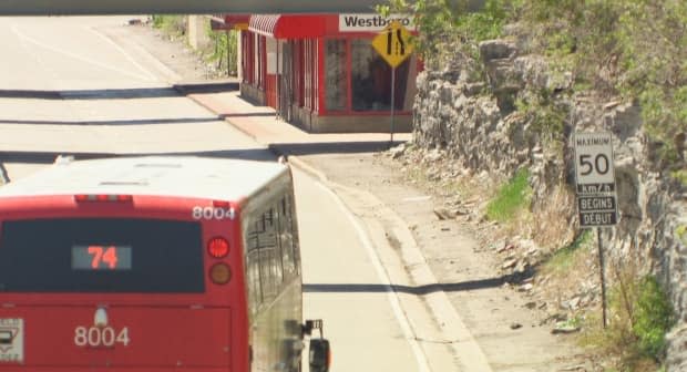 A westbound double-decker pulls into Westboro station on May 13, 2021. The posted speed limit is 50 km/h and there are no visible changes to the placement of the shelter or structure of the platform from 2019.