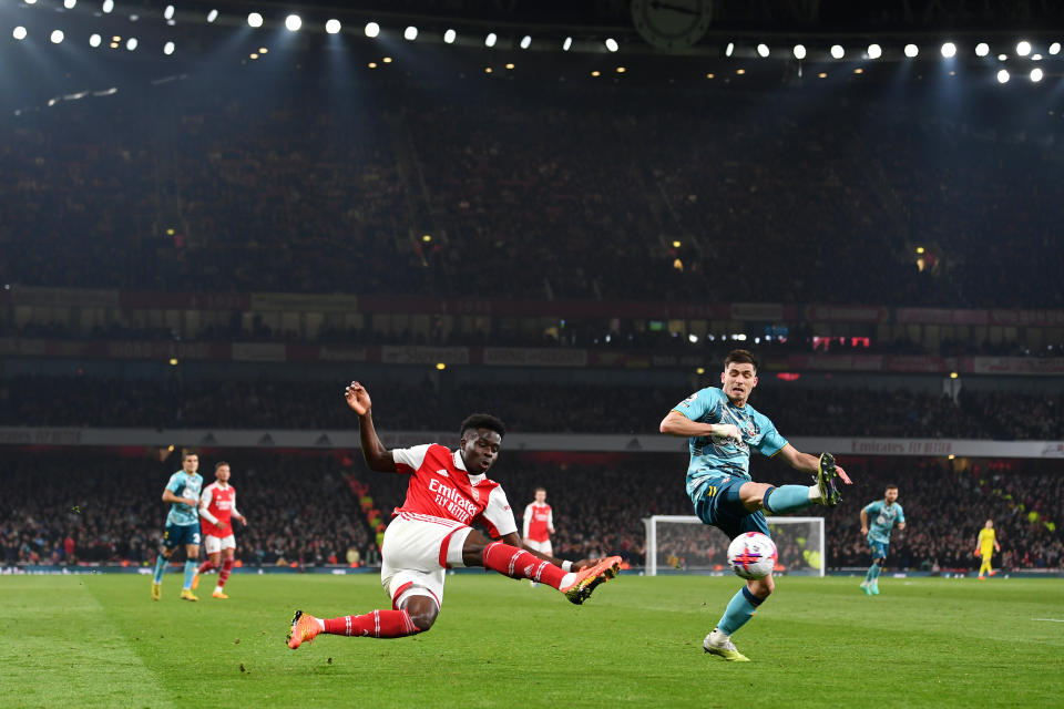 LONDON, ENGLAND - APRIL 21: Bukayo Saka of Arsenal shoots under pressure from Romain Perraud of Southampton during the Premier League match between Arsenal FC and Southampton FC at Emirates Stadium on April 21, 2023 in London, England. (Photo by David Price/Arsenal FC via Getty Images)