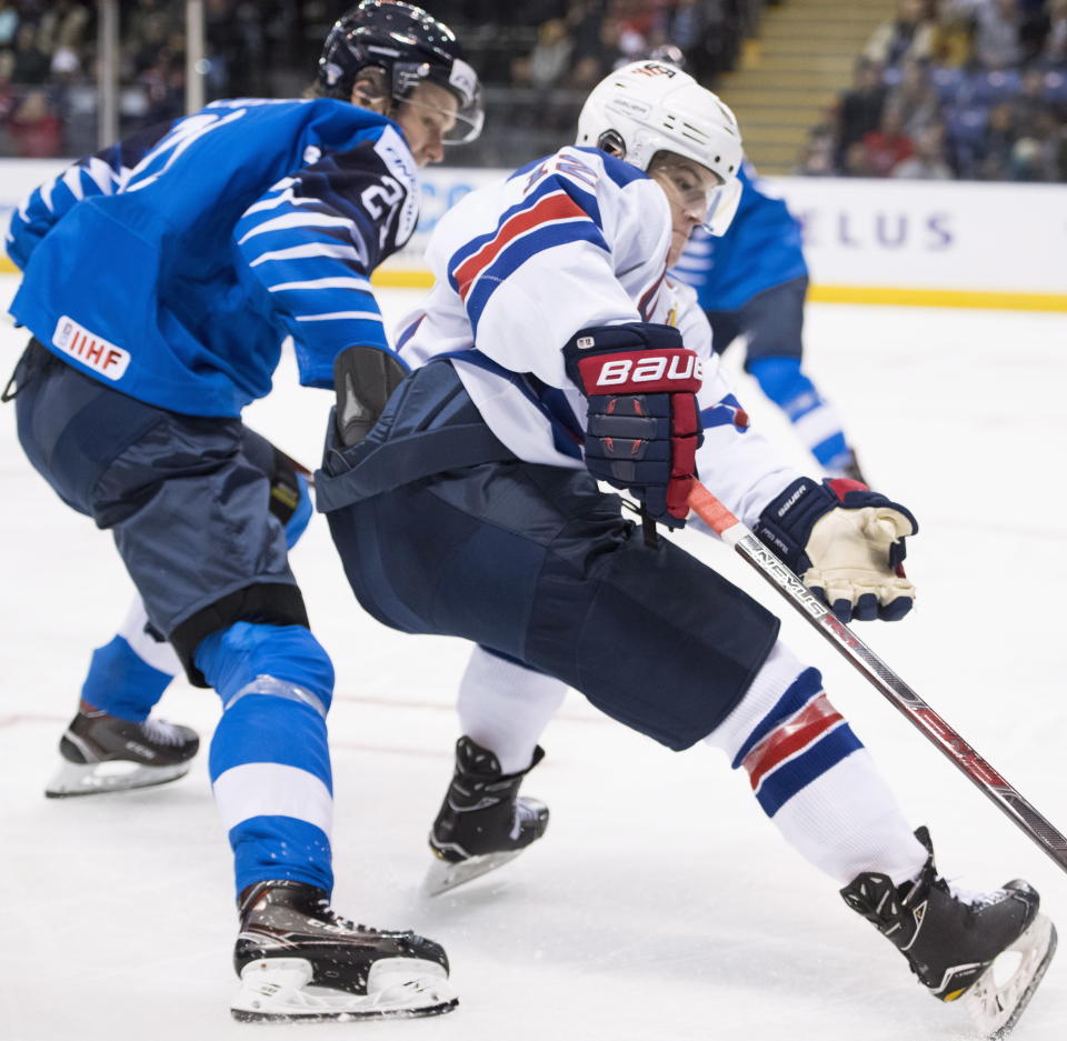 United States' Logan Cockerill (12) fights for control of the puck with Finland's Otto Latvala (21) during the second period of a world junior hockey championships game in Victoria, British Columbia, Monday, Dec. 31, 2018. (Jonathan Hayward/The Canadian Press via AP)