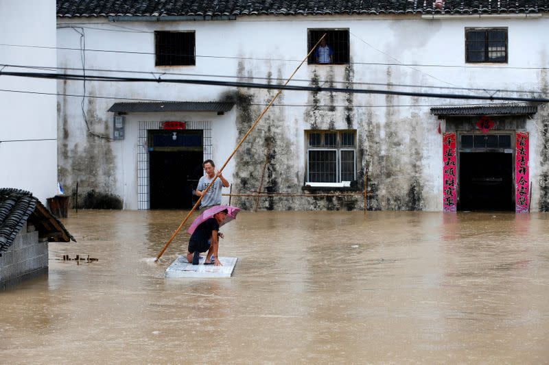 People are seen on a makeshift raft in a flooded village following heavy rainfall in Huangshan