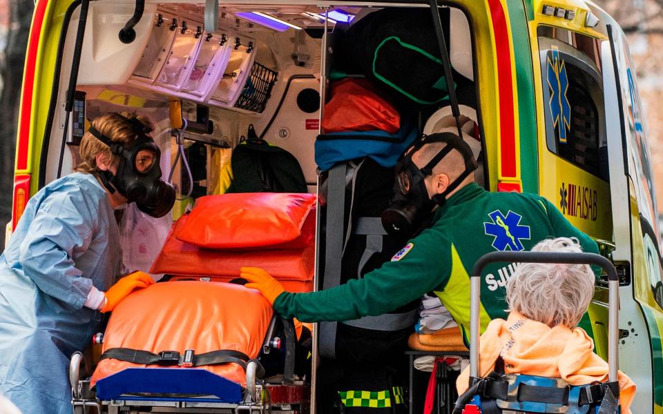 Paramedics with protective gas masks help to transport a patient  - AFP