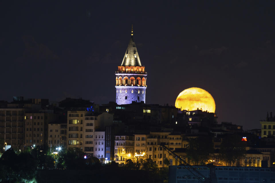 The moon rises over Istanbul's skyline with the iconic Galata Tower, Friday, May 8, 2020, a few hours before the start of a two-day curfew declared by the government in an attempt to control the spread of coronavirus. The full moon, also known as the supermoon or Flower Moon, was visible on Thursday, May 7. (AP Photo/Emrah Gurel)