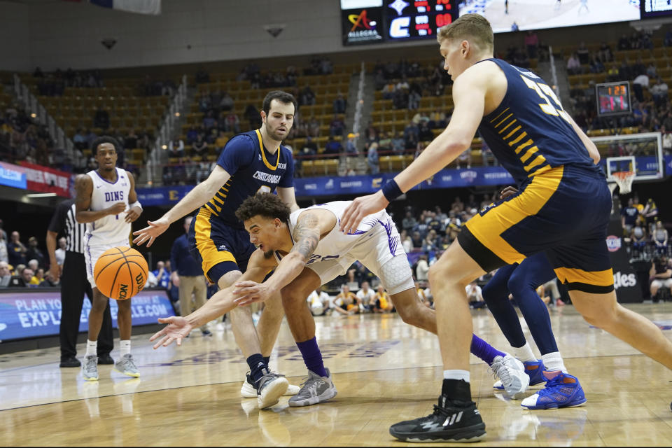 Furman forward Jalen Slawson, center, reaches for the ball ahead of Chattanooga guard A.J. Caldwell, front left, and center Jake Stephens (33) during the second half of an NCAA men's college basketball championship game for the Southern Conference tournament, Monday, March 6, 2023, in Asheville, N.C. (AP Photo/Kathy Kmonicek)