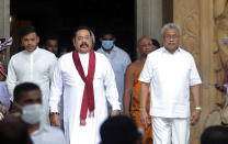 Sri Lanka’s former President Mahinda Rajapaksa, center, leaves with his younger brother, President Gotabaya Rajapaksa, right, after being sworn in as the prime minister at Kelaniya Royal Buddhist temple in Colombo, Sri Lanka, Sunday, Aug. 9, 2020. (AP Photo/Eranga Jayawardena)