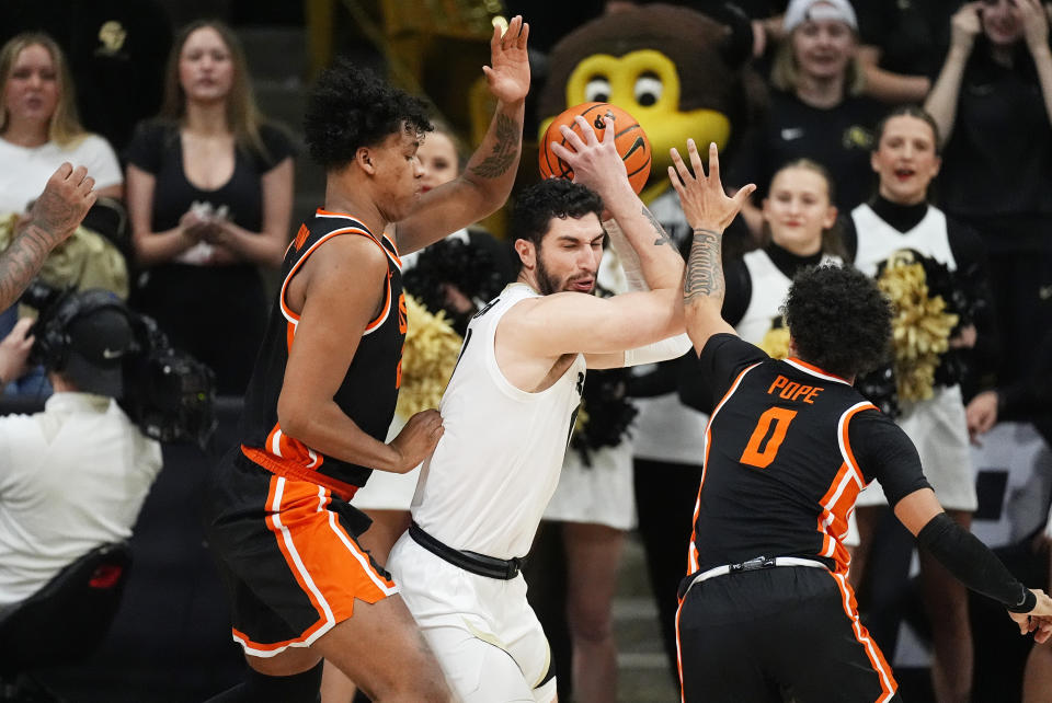 Colorado guard Luke O'Brien, center, is trapped with the ball by Oregon State forward Thomas Ndong, left, and guard Jordan Pope, right, in the first half of an NCAA college basketball game Saturday, Jan. 20, 2024, in Boulder, Colo. (AP Photo/David Zalubowski)