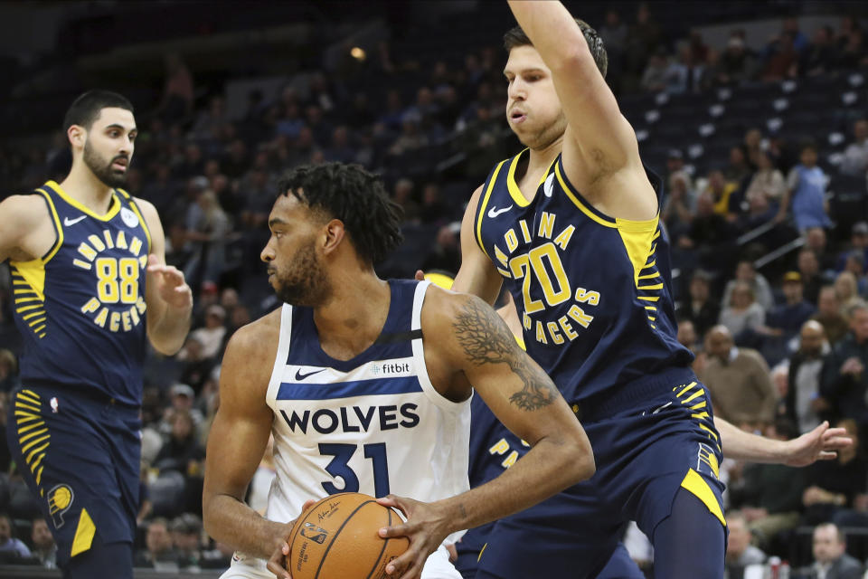 Minnesota Timberwolves' Keita Bates-Diop, center, looks for help as Indiana Pacers' Doug McDermott, right, looms over him in the first half of an NBA basketball game Wednesday, Jan. 15, 2020, in Minneapolis. (AP Photo/Jim Mone)