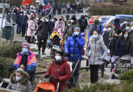 Families queue up in front of the entrance to the Opel Zoo before its reopening in Kronberg, Germany, Monday, March 8, 2021. The extensive measures to protect against infection with the corona virus have been relaxed somewhat in Hesse. On the first opening day after the lockdown, the rush was great. Visitors were able to buy their tickets for the zoo visit via an online ticket system. (Arne Dedert/dpa via AP)