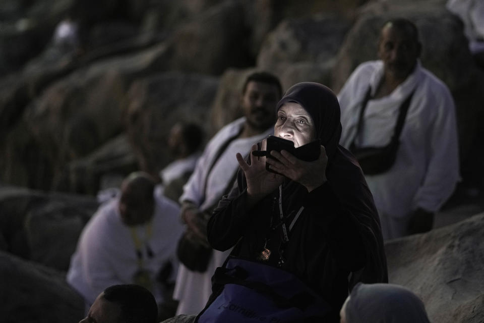 A Muslim pilgrim makes a video call on the rocky hill known as the Mountain of Mercy, on the Plain of Arafat, during the annual Hajj pilgrimage, near the holy city of Mecca, Saudi Arabia, Tuesday, June 27, 2023. Muslim pilgrims in Mecca circled the Kaaba, Islam's holiest site, and then converged on a vast tent camp in the nearby desert, officially opening the annual Hajj pilgrimage on Monday, returning to its full capacity for the first time since the coronavirus pandemic. (AP Photo/Amr Nabil)