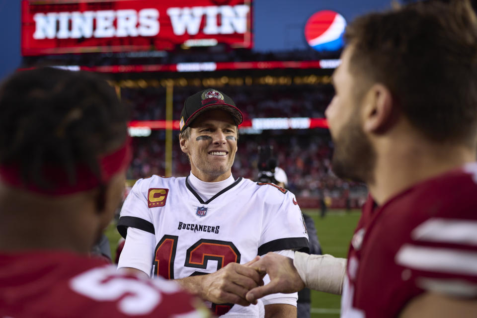 SANTA CLARA, CA - DECEMBER 11: Tom Brady #12 of the Tampa Bay Buccaneers speaks with members of the San Francisco 49ers during the second half at Levi's Stadium on December 11, 2022 in Santa Clara, California. (Photo by Cooper Neill/Getty Images)