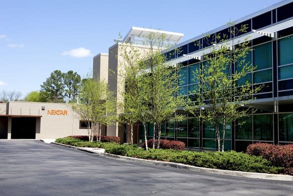 Two-story office building with landscaping and Nektar logo on wall.