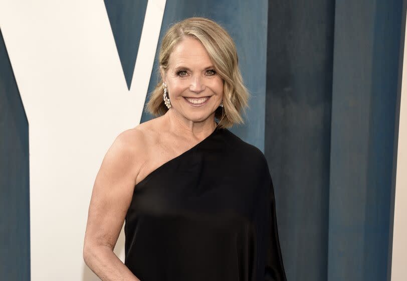 A woman with short blond hair posing in a black dress