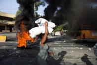 <p>A woman carries items during a protest over the cost of fuel in Port-au-Prince, Haiti, Saturday, July 7, 2018. (Photo: Dieu Nalio Chery/AP) </p>